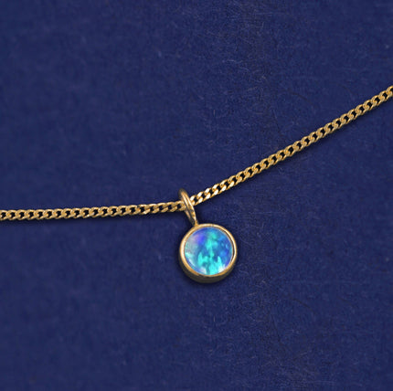A 14k yellow gold Opal Necklace on a dark blue background