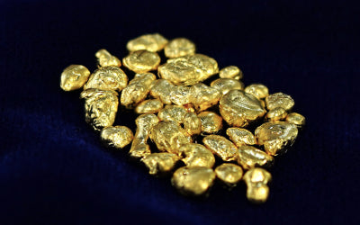 Raw gold nuggets on a dark blue cloth background