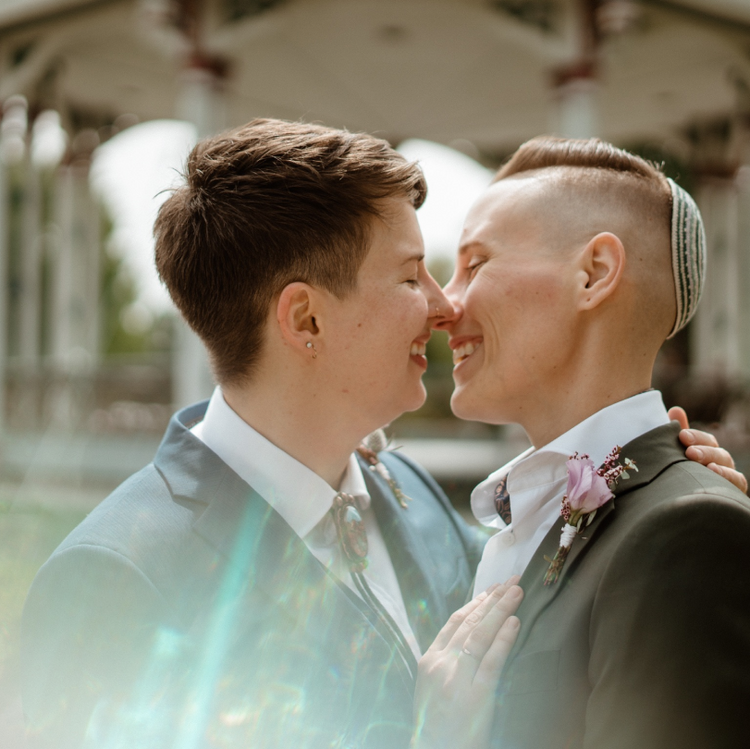 Two people leaning in for a kiss while wearing Automic Gold wedding bands