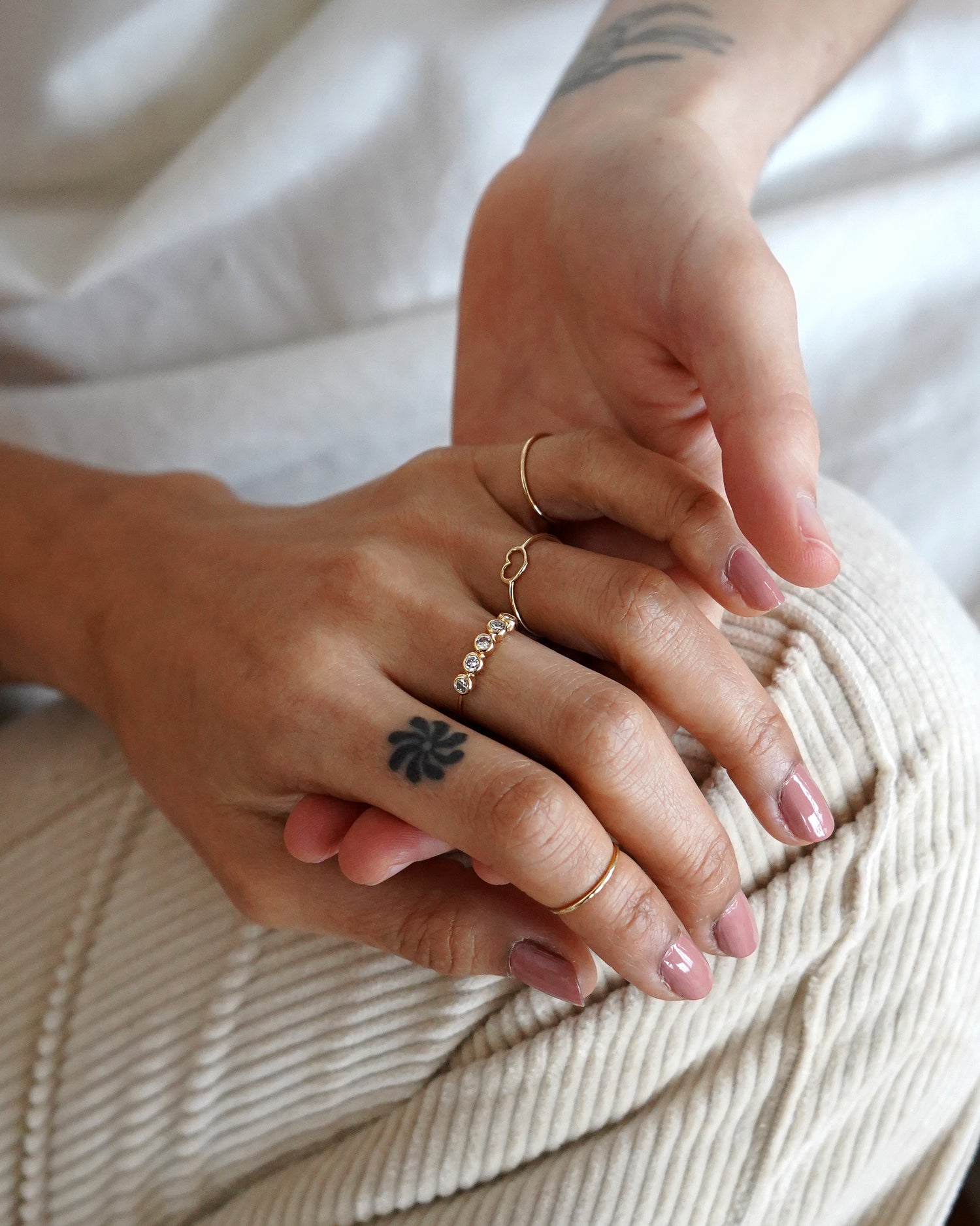 Close up view of two tattooed models holding hands wearing 14k solid gold ring