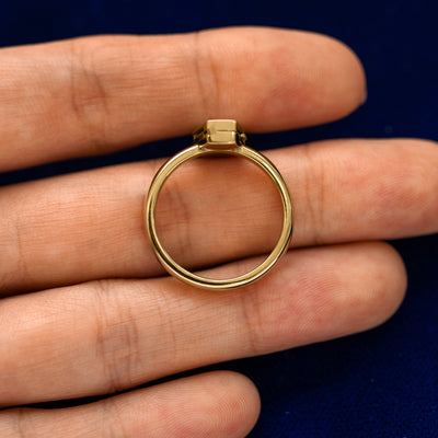 A yellow gold Coffin Ring in a model's hand showing the thickness of the ban