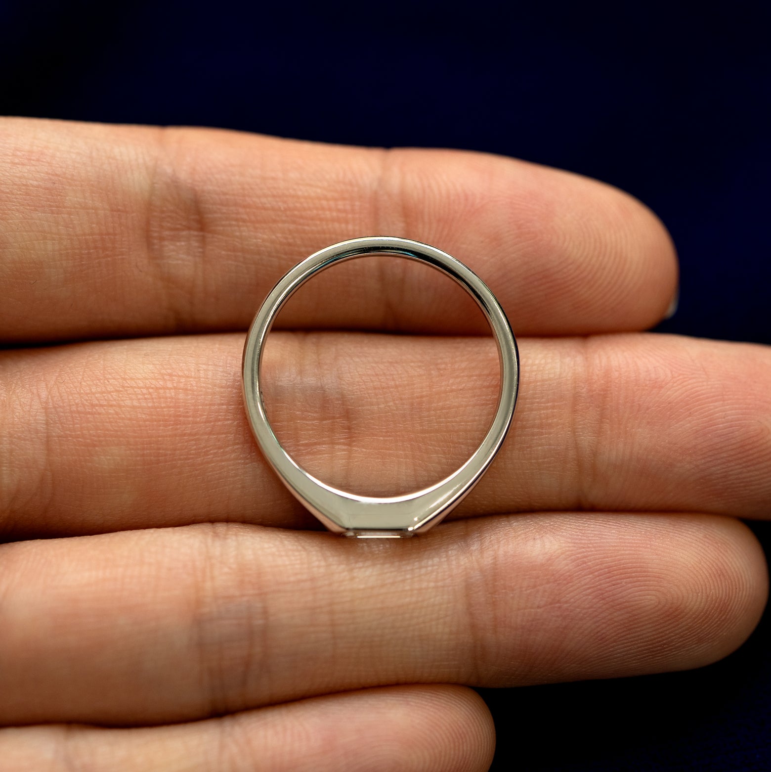 An Emerald Cut Lab Created Diamond Signet Ring laying in a model's hand to show the thickness of the band