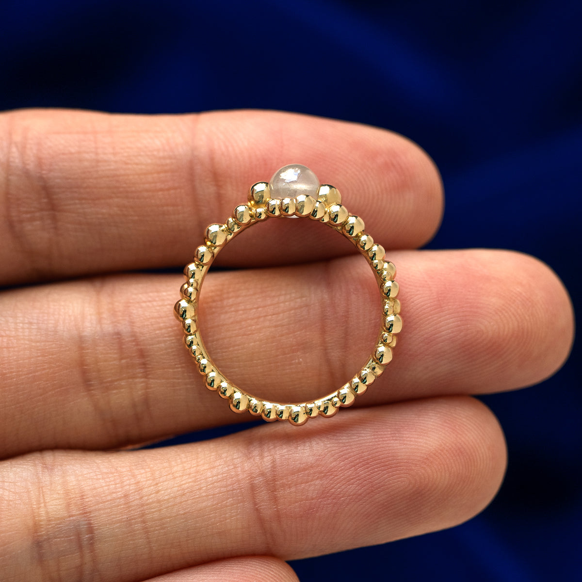 A diamond bead bubble ring lying flat in a models hand to show the thickness of the ring