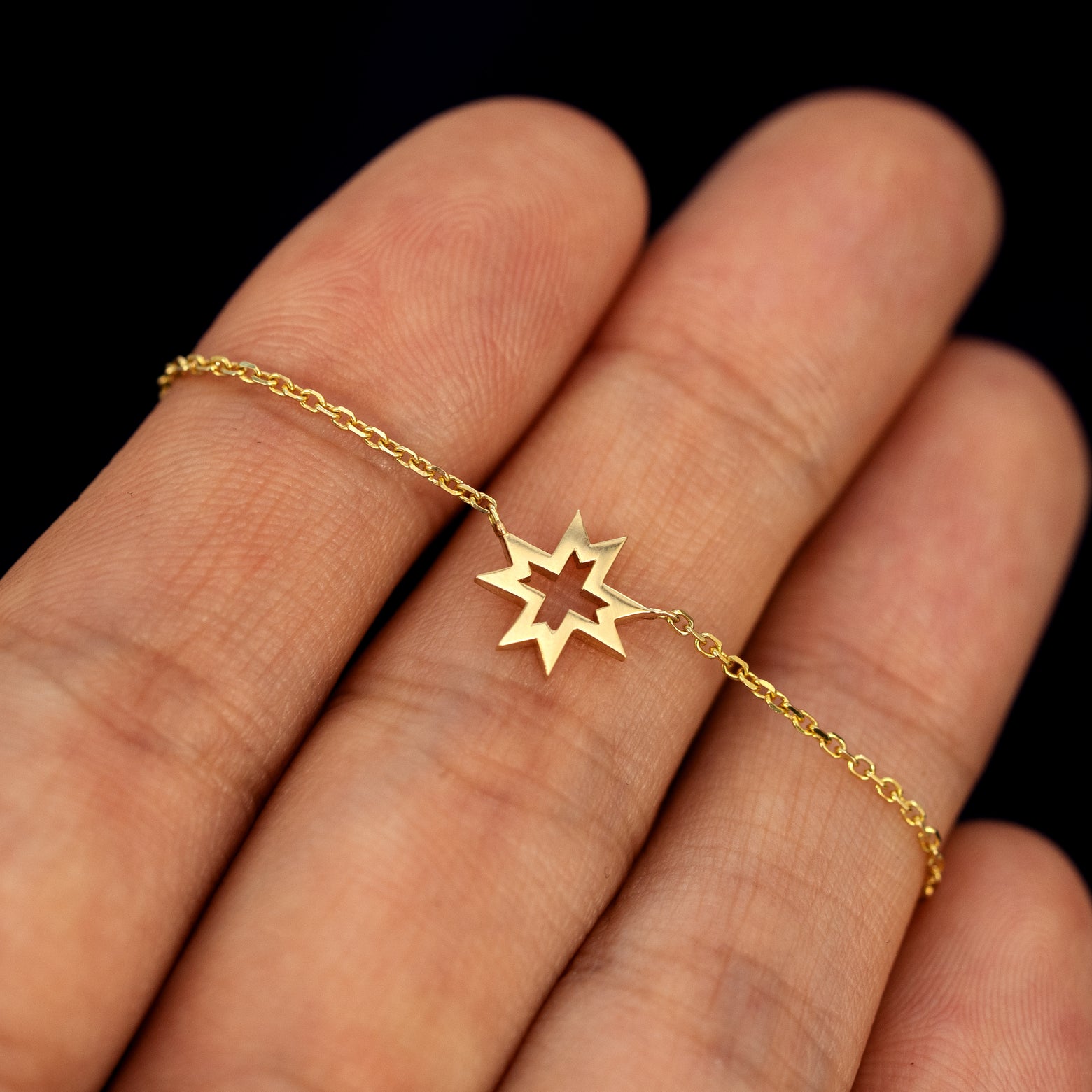 An 8 pointed star necklace laying across a model's fingers to show the larger star details