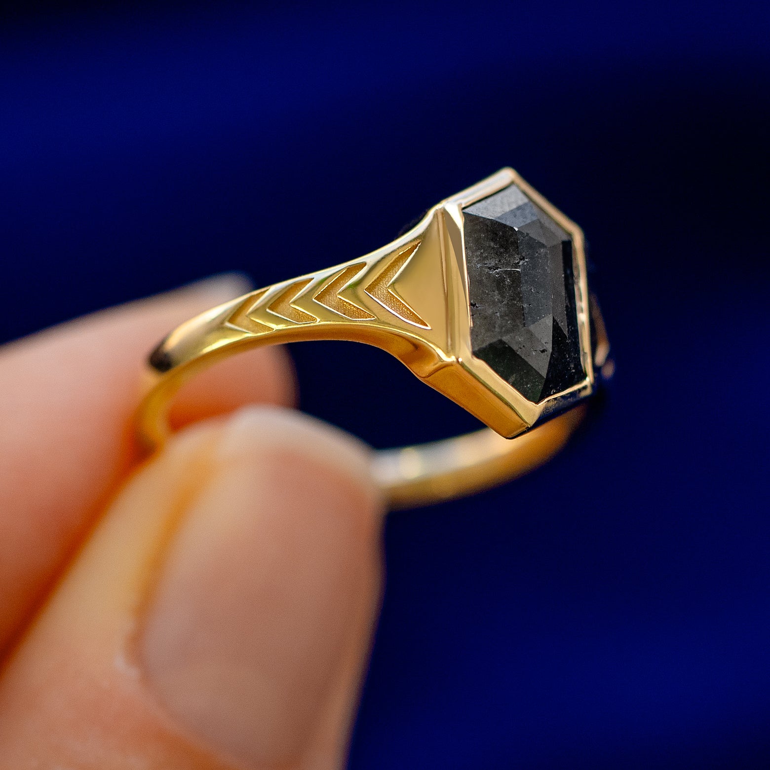 A model holding a 14k gold Chronos Ring sideways to show the details of the bezel setting and the stone