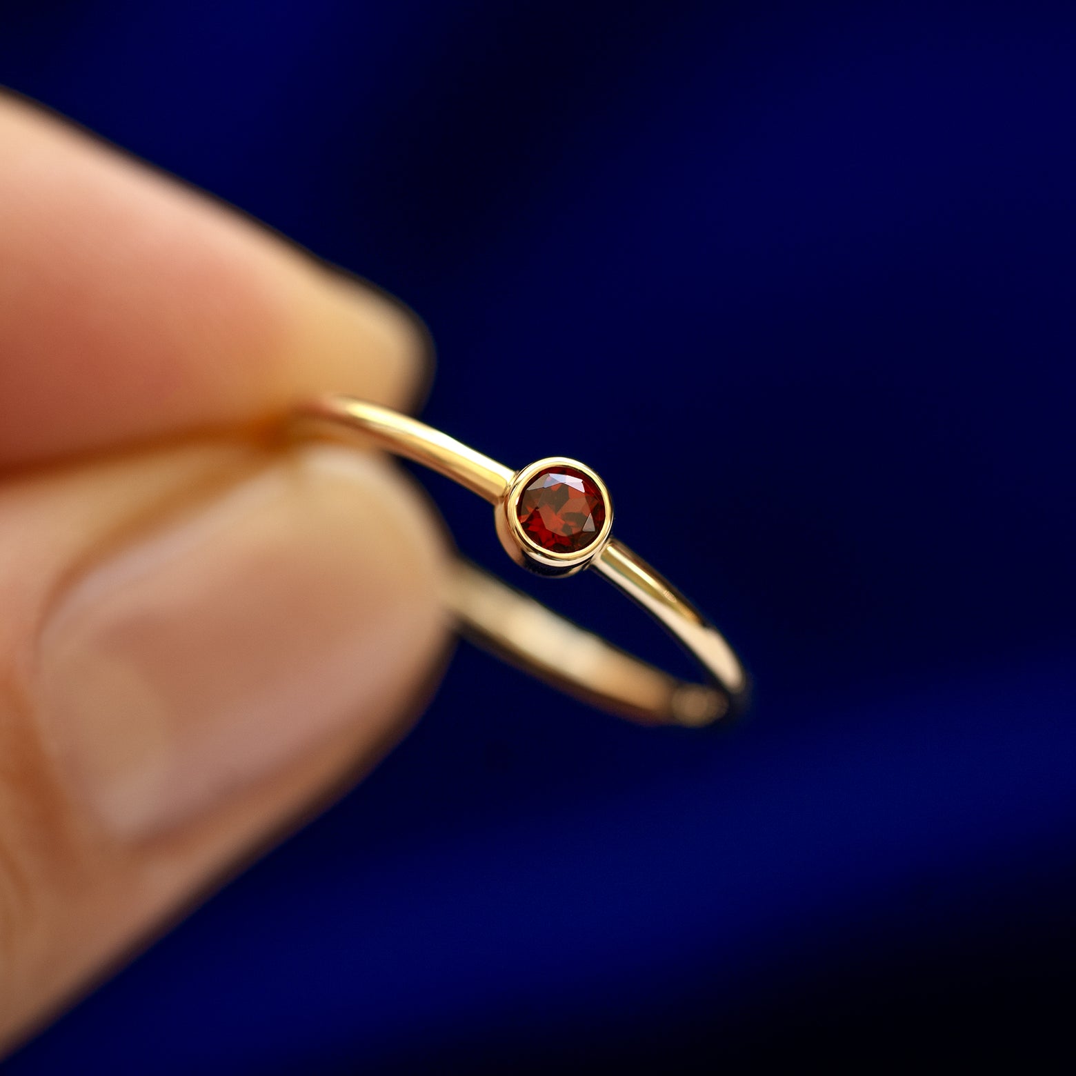 A model holding a Garnet Ring tilted to show the bezel setting