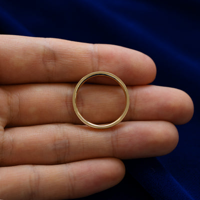 A geometric grass band lying flat in a models hand to show the thickness of the ring