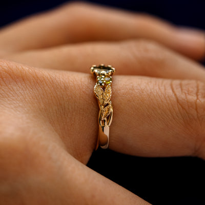 Side view of a Green Sapphire Leaves and Vines Ring on a model's finger