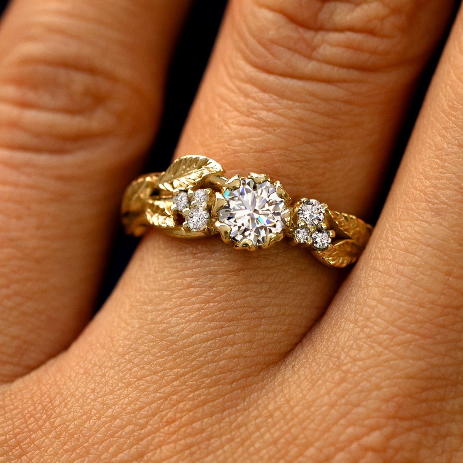 Close up view of a model's fingers wearing a 14k gold Clear Diamond Leaves and Vines Ring