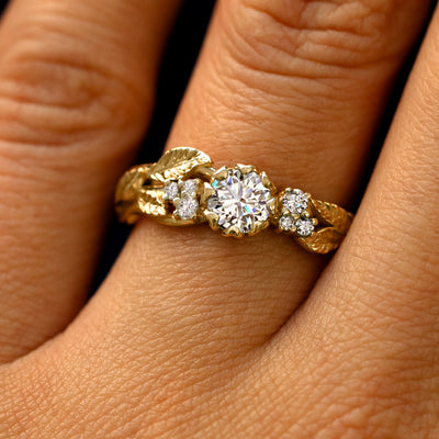 Close up view of a model's fingers wearing a 14k gold Clear Diamond Leaves and Vines Ring