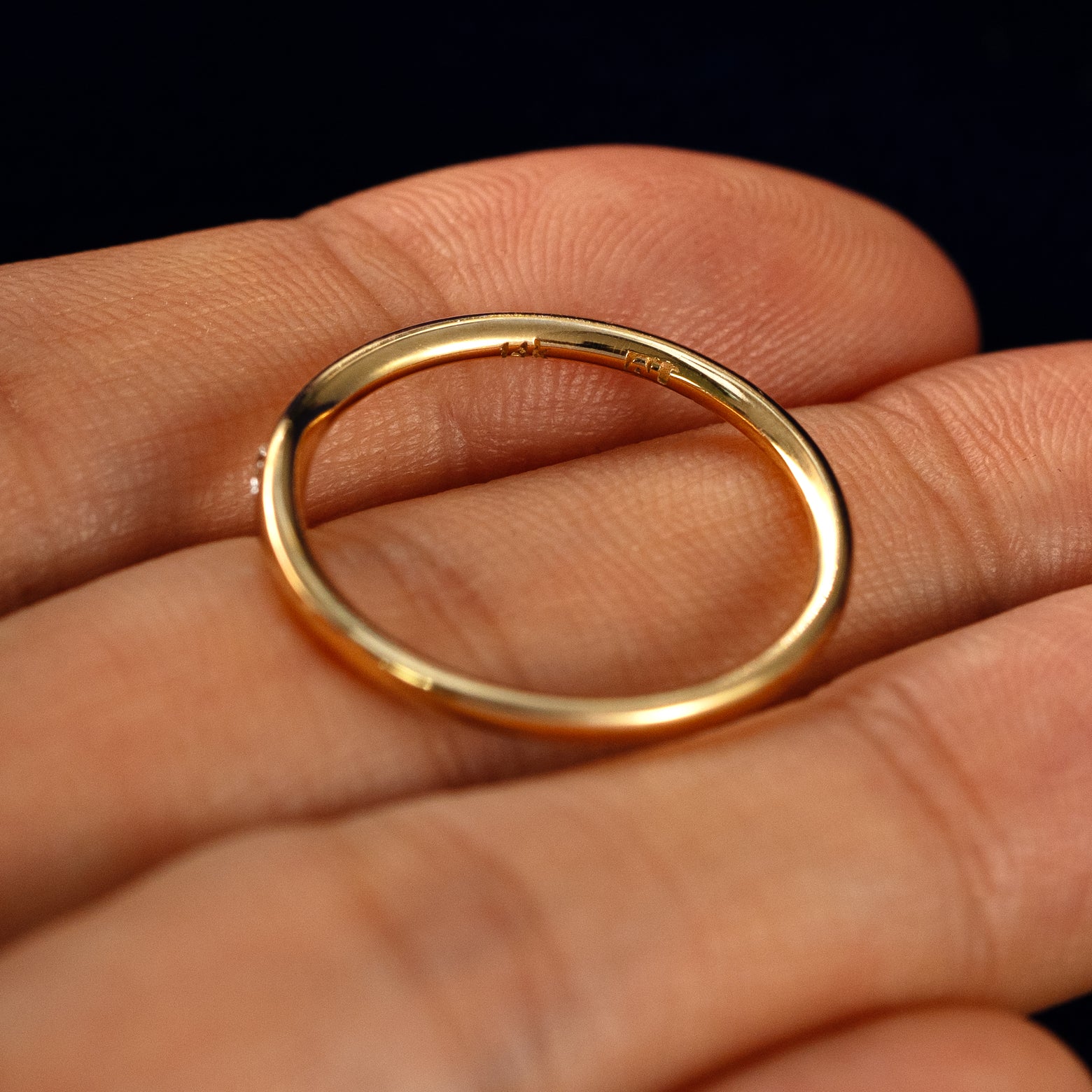 A Flush Set Oval Diamond Ring in a model's hand showing the inside of the band