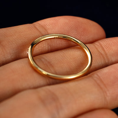 A Flush Set Oval Diamond Ring in a model's hand showing the inside of the band