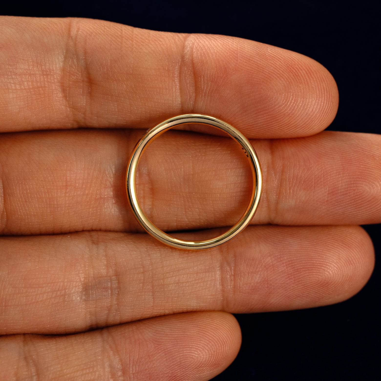 A Flush Set Round Diamond Ring in a model's hand showing the thickness of the band
