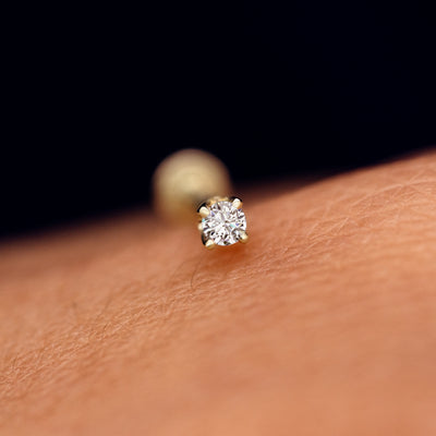 A solid 14k yellow gold 2mm Diamond Flatback Piercing resting on the back of a model's hand