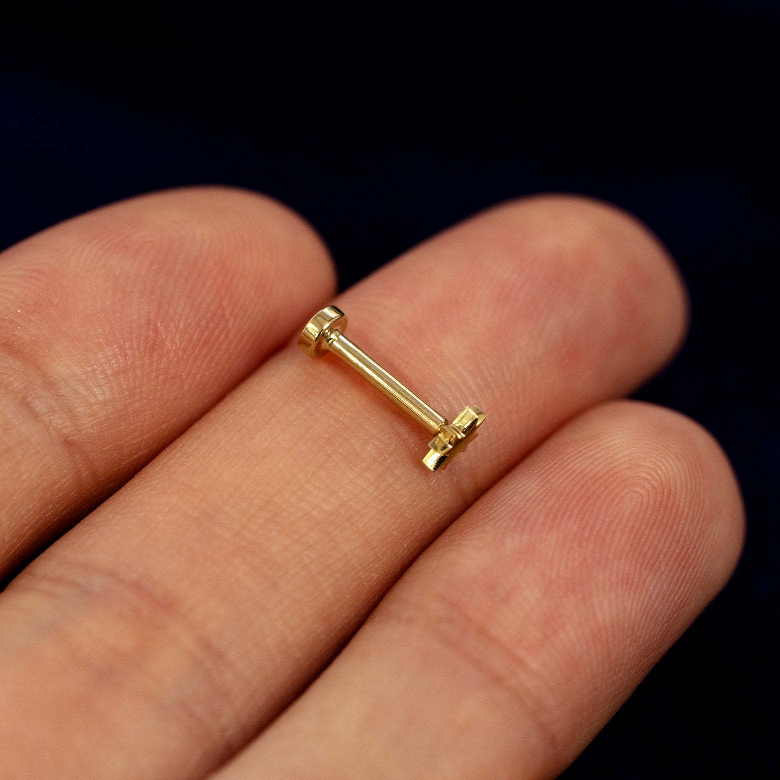 A model holding an 8 pointed star flatback piercing sideways on their fingers to show details