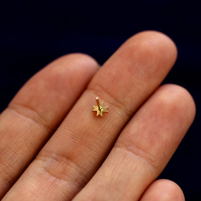 A model holding an 8 pointed star flatback piercing face down on their fingers to show details
