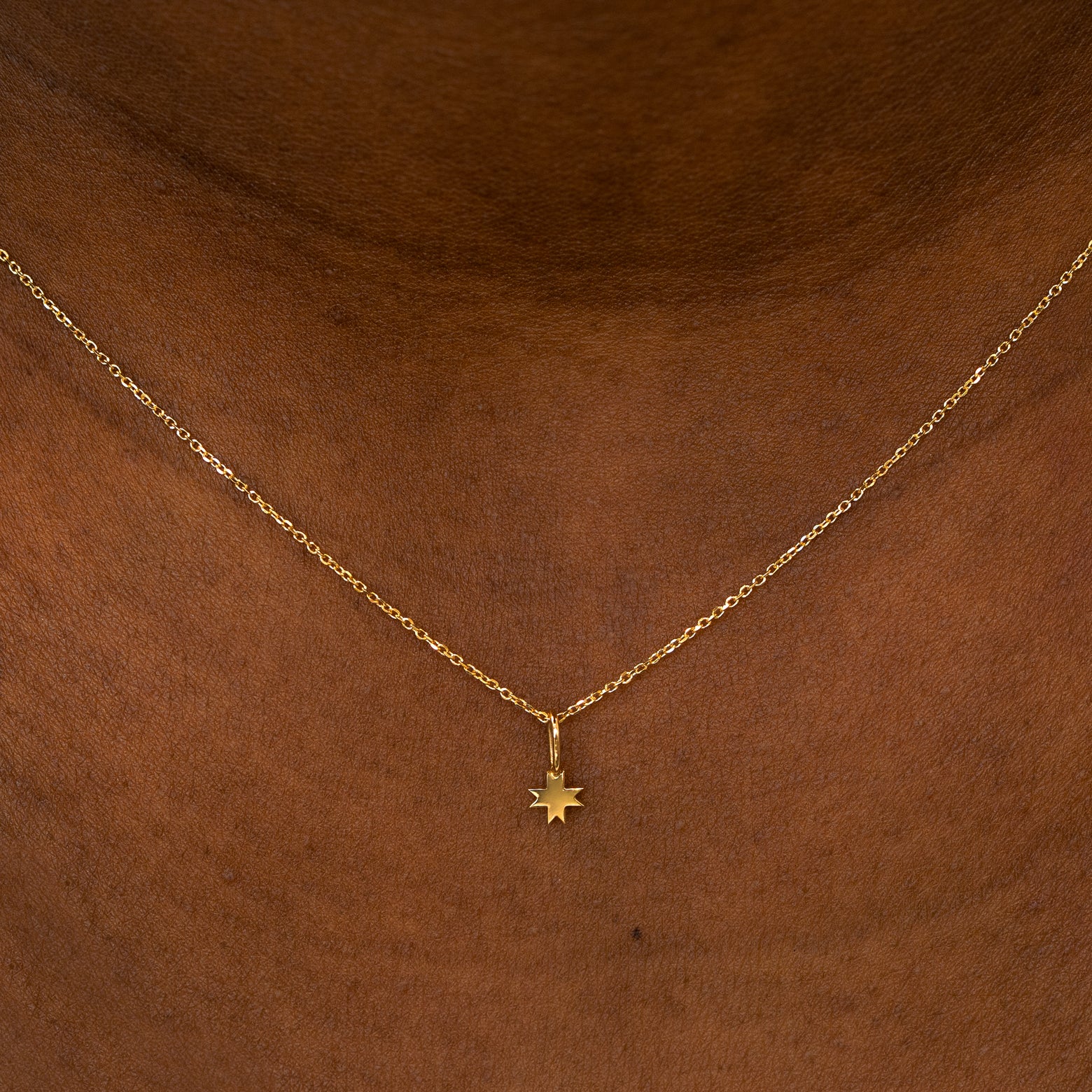 A model wearing a 14k yellow gold 8 Pointed Star Charm on a Cable Chain Necklace