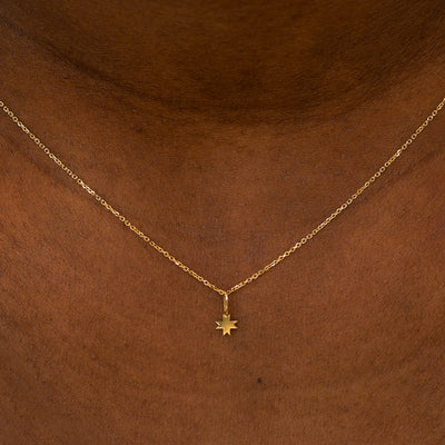 A model wearing a 14k yellow gold 8 Pointed Star Charm on a Cable Chain Necklace