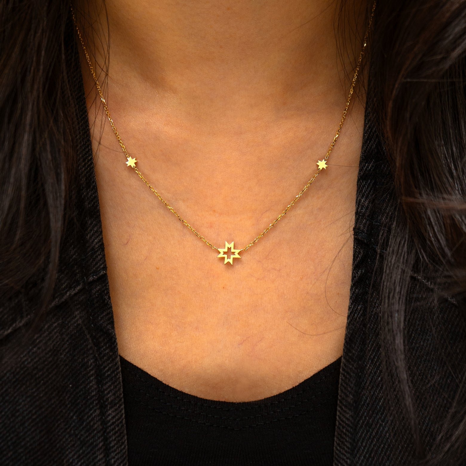 A model wearing a yellow gold 8 pointed stars station necklace