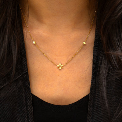 A model wearing a yellow gold 8 pointed stars station necklace