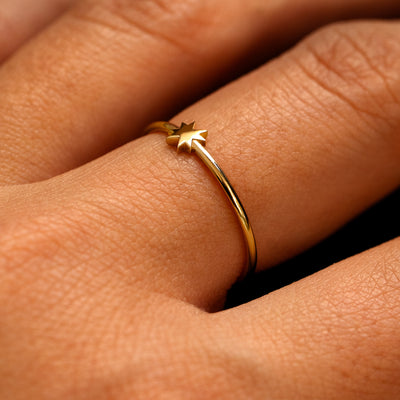Side view of a models fingers wearing a 14k gold 8 pointed star ring