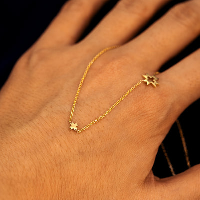 A model showing the design of an 8 pointed star necklace by wearing it on the back of their hand