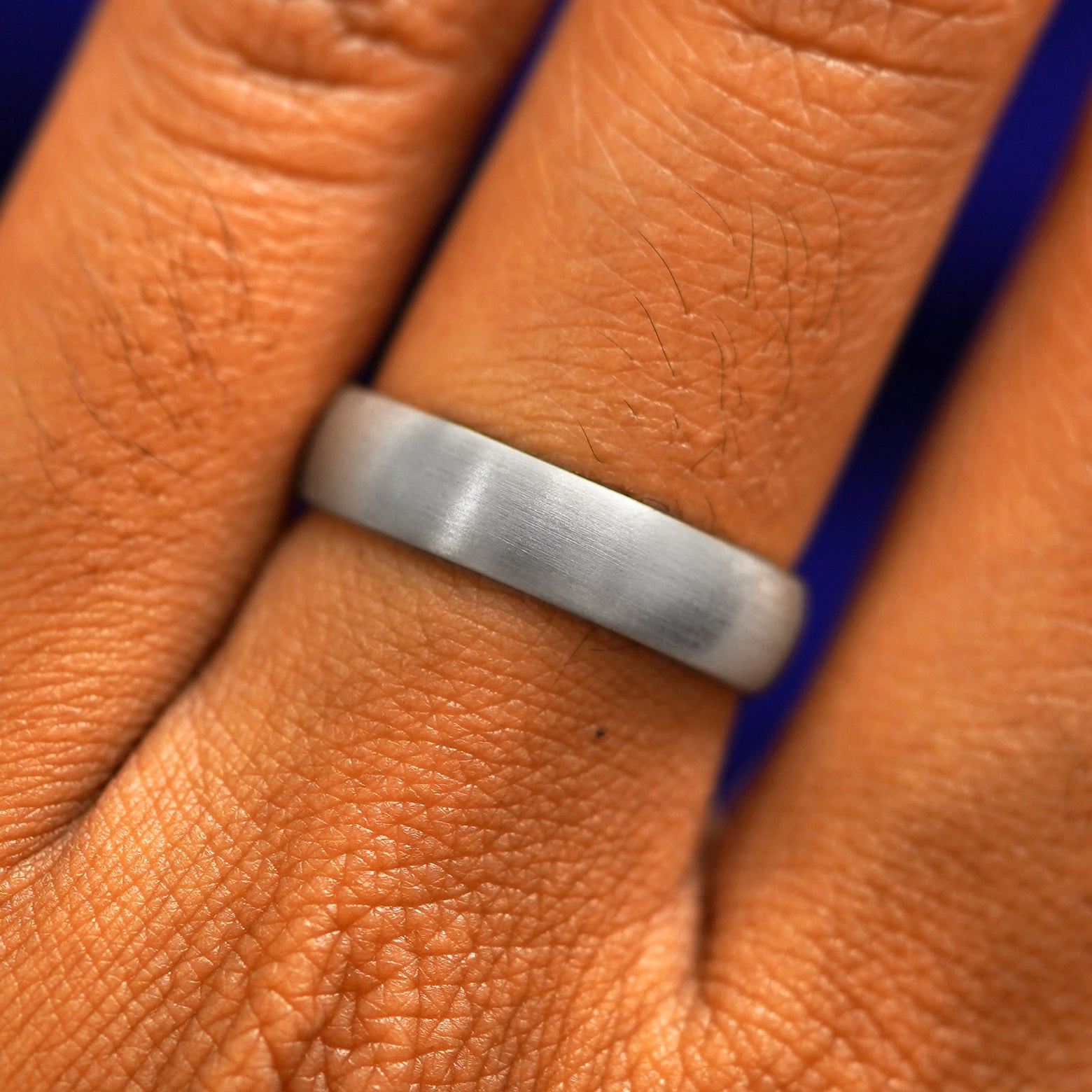 Close up view of a model's fingers wearing a 4mm 925 silver Curvy Matte Band