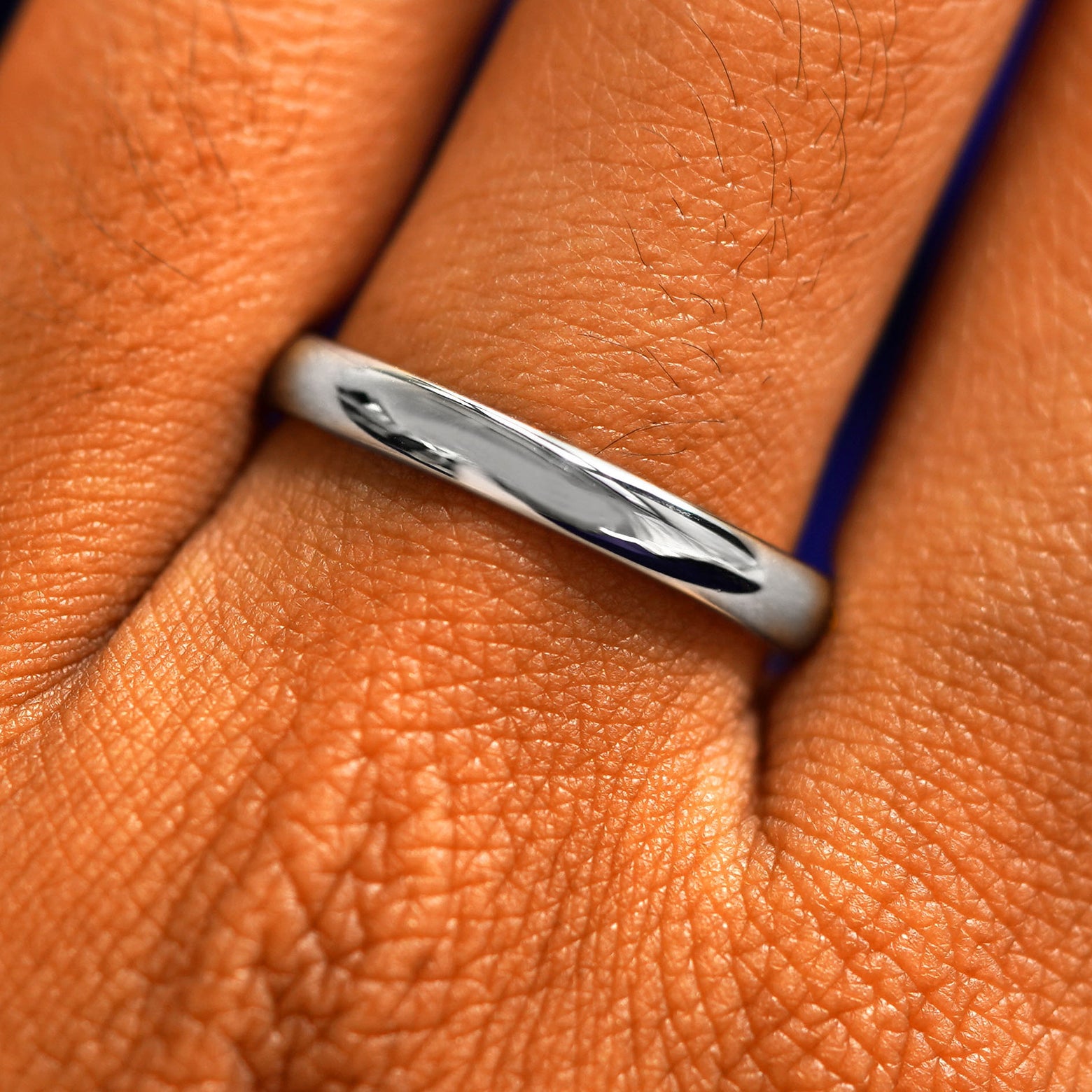 Close up view of a model's fingers wearing a 2mm 925 silver Curvy Mirror Band