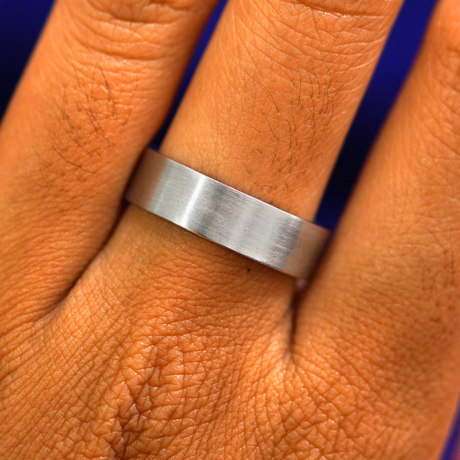Close up view of a model's fingers wearing a 4mm 925 sterling silver Industrial Matte Band