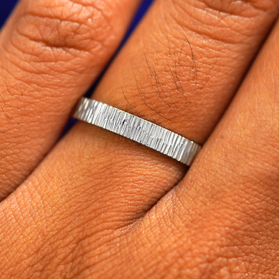 Close up view of a model's fingers wearing a 2mm 925 silver Industrial Wood Band