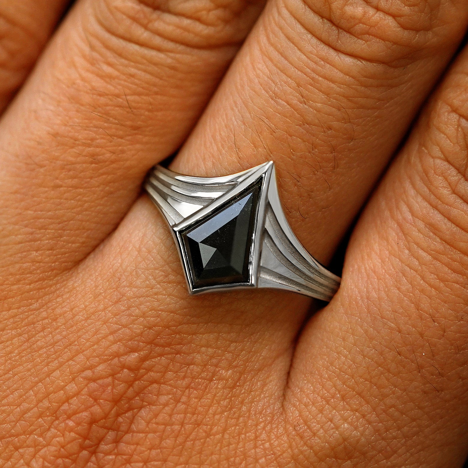 Close up view of a model's fingers wearing a 925 silver kite black diamond engraved journey ring