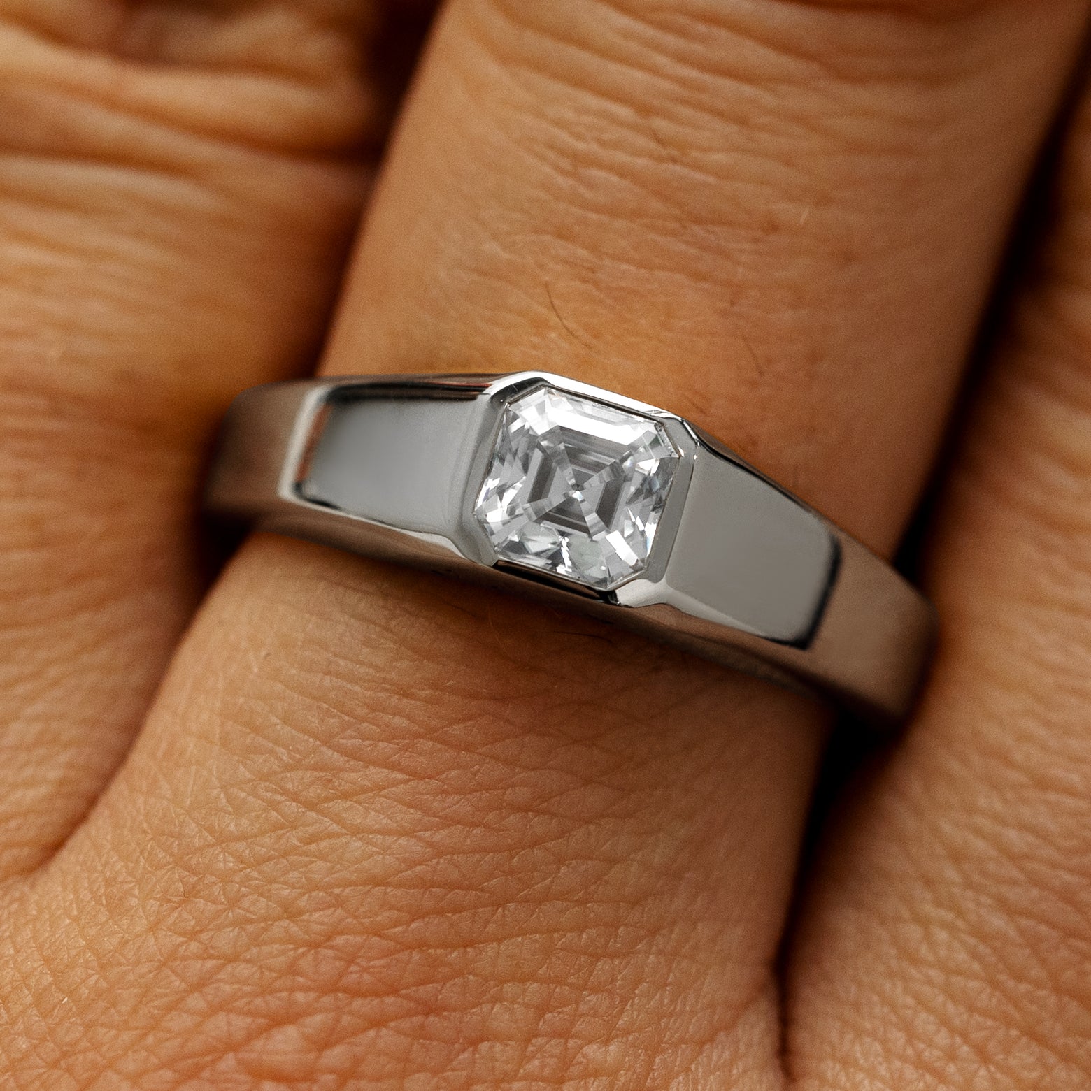 Close up view of a models hand wearing a 950 platinum asscher lab gemstone ring
