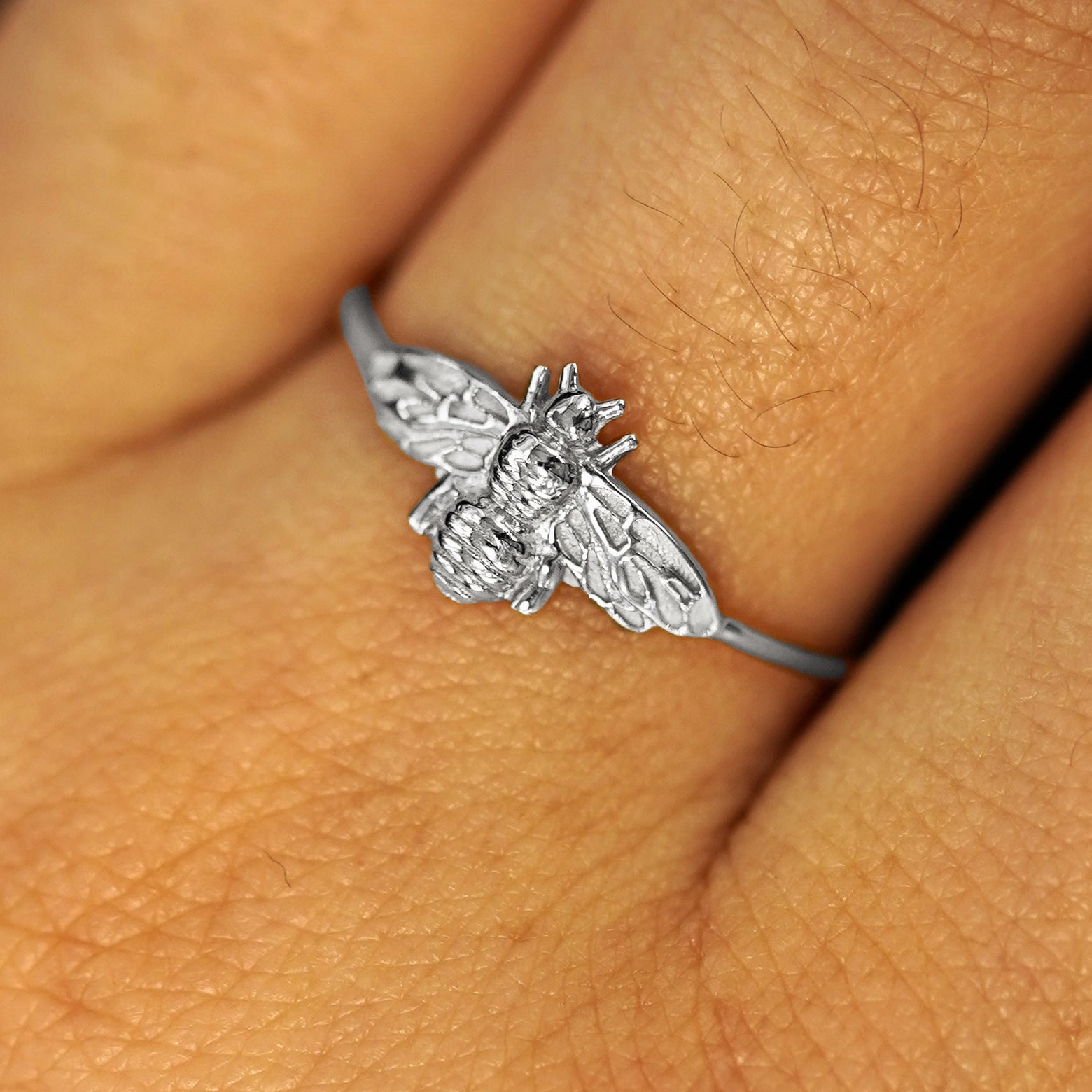 Close up view of a model's fingers wearing a solid platinum Bee Ring