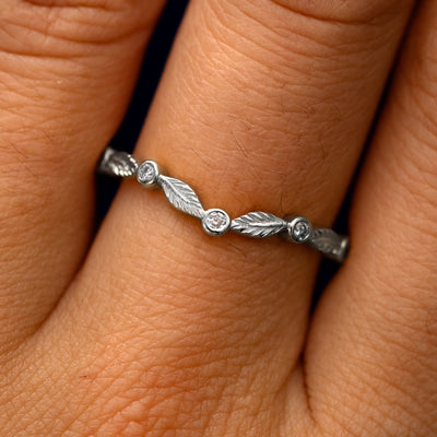 Close up view of a model's fingers wearing a 950 platinum Chevron Leaves and Round Diamonds Band