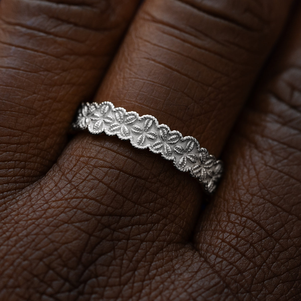 Close up view of a model wearing a solid 950 platinum cowrie shell flower and rope band
