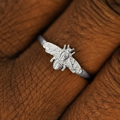 Close up view of a model's hand wearing a 950 platinum Curvy Bee Ring