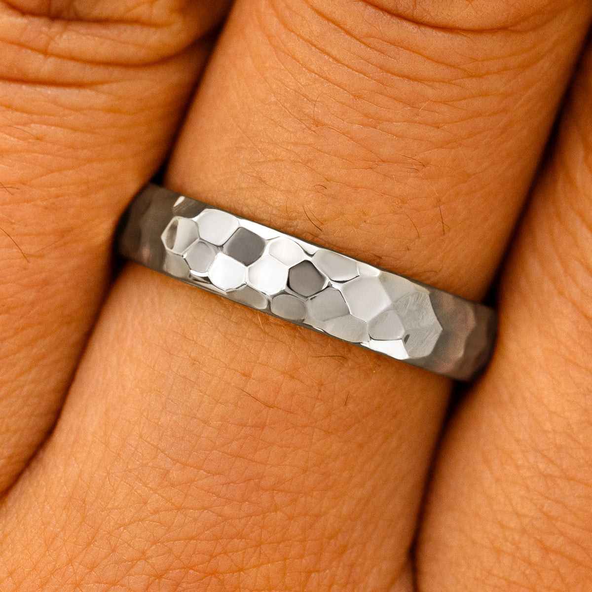 Close up view of a model's fingers wearing a platinum Curvy Hammered Band