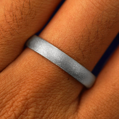 Close up view of a model's fingers wearing a 950 Platinum Curvy Stardust Band