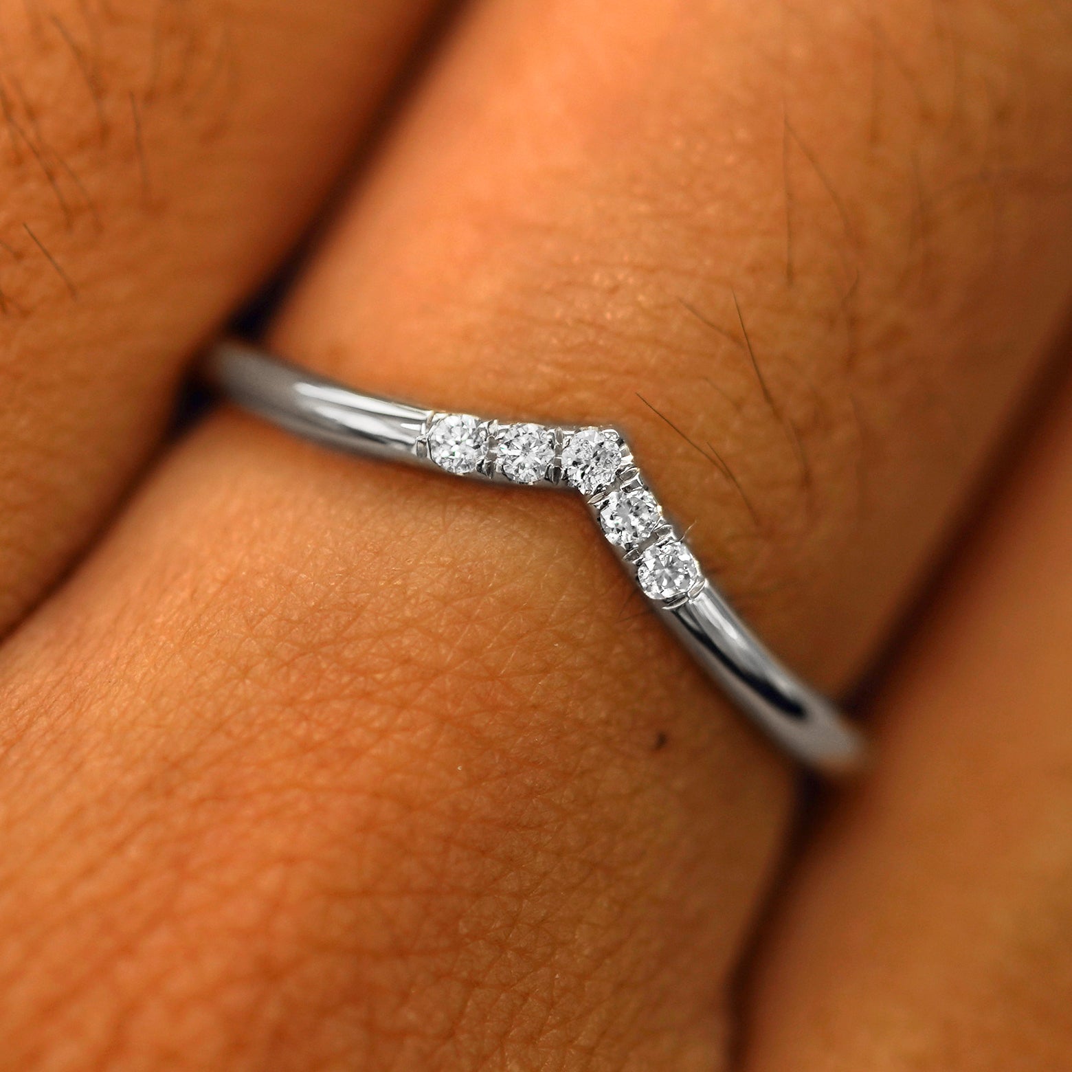 Close up view of a model's fingers wearing a 950 platinum Diamond Chevron Band