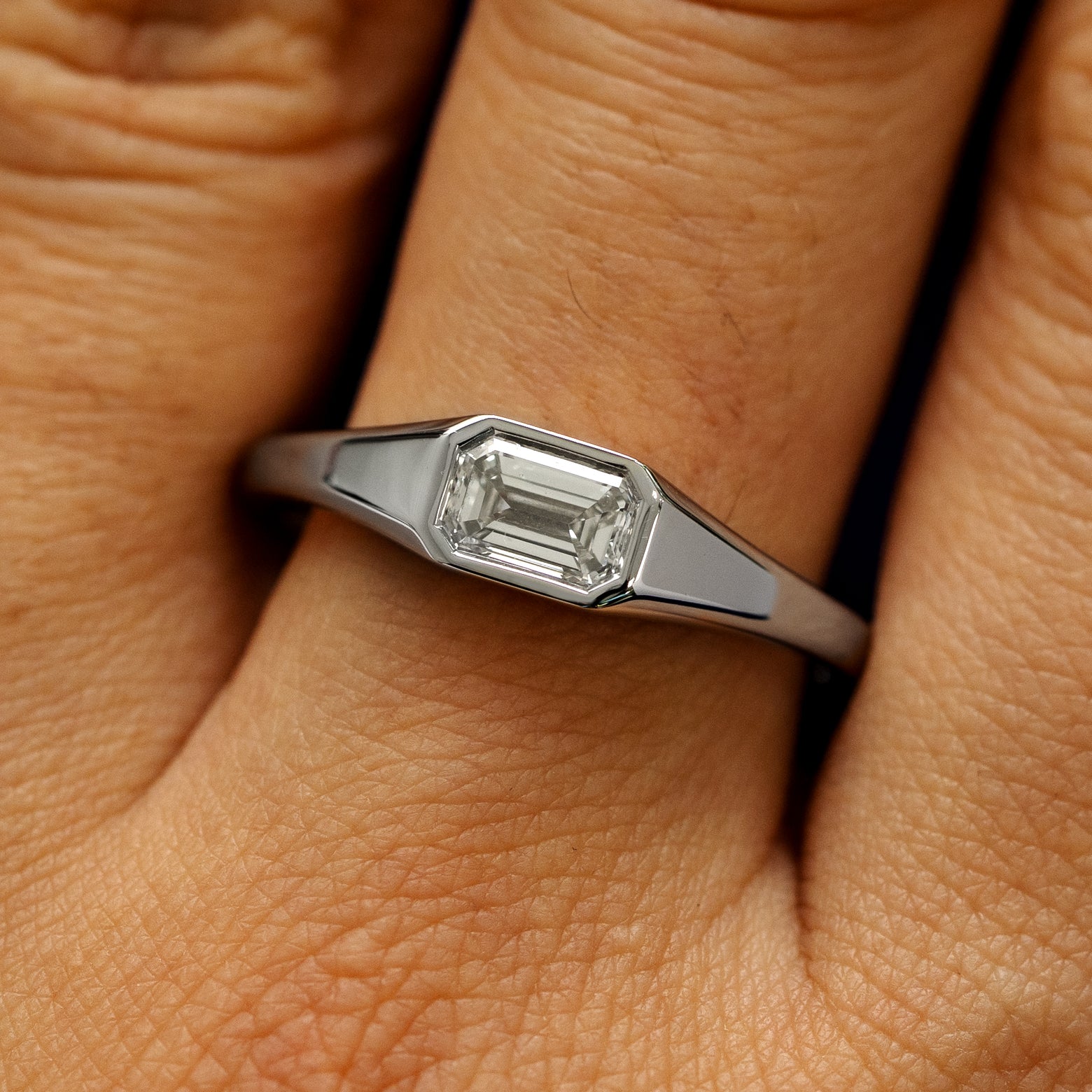 Close up view of a model's fingers wearing a 950 platinum Emerald Cut Lab Created Diamond Signet Ring