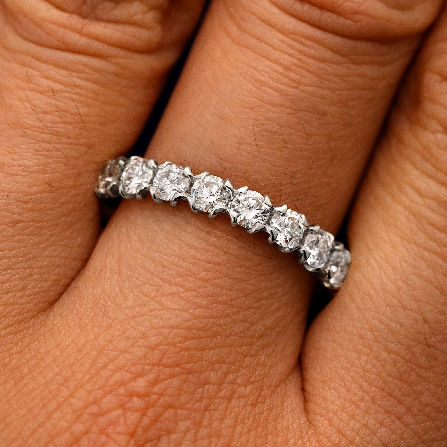 Close up view of a model's fingers wearing a 950 platinum Petal Set Diamond Eternity Band