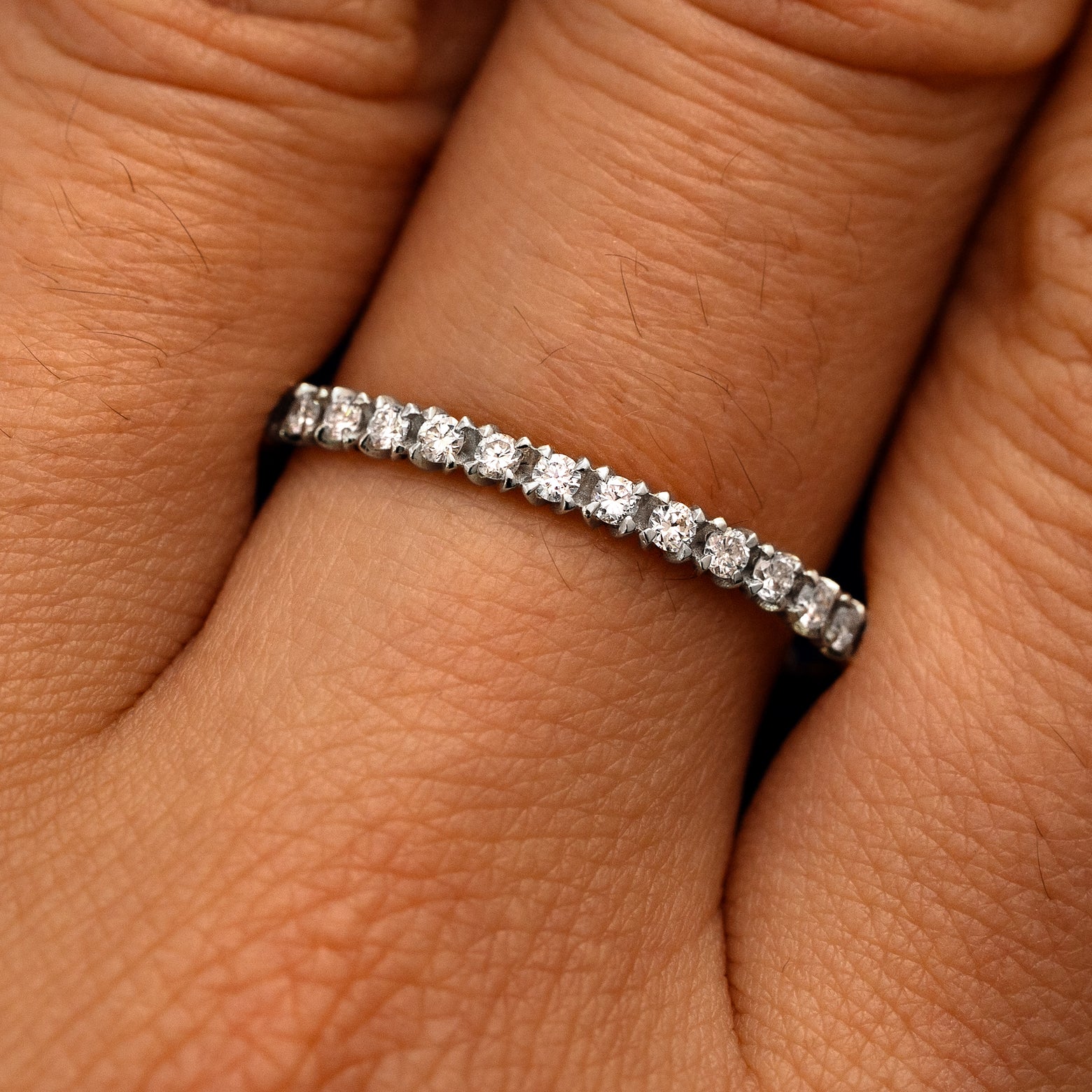Close up view of a model's fingers wearing a 950 platinum Mini Petal Set Diamond Eternity Band