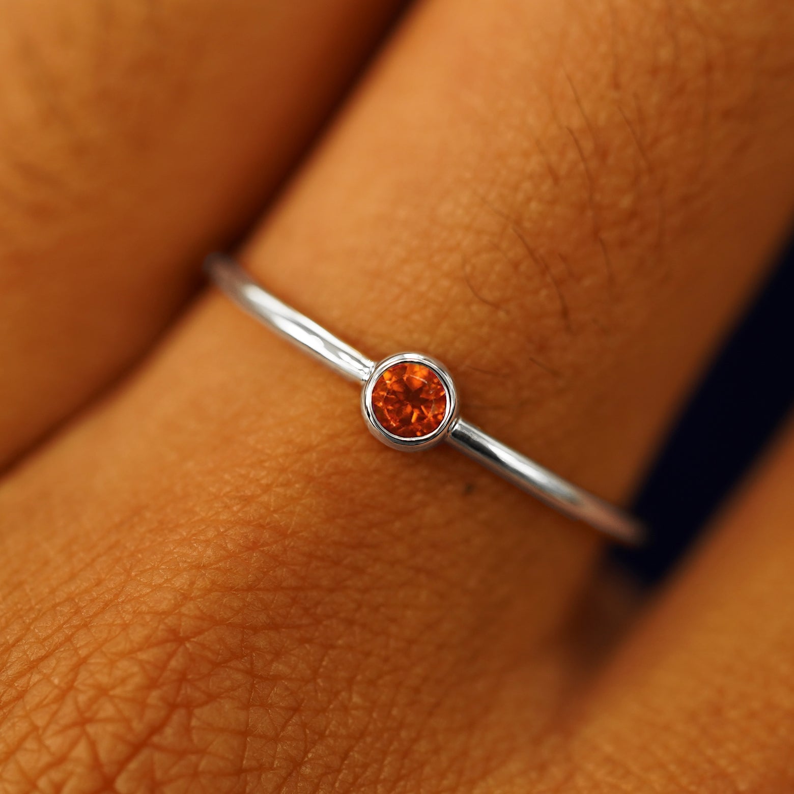 Close up view of a model's fingers wearing a 950 platinum Fire Opal Ring