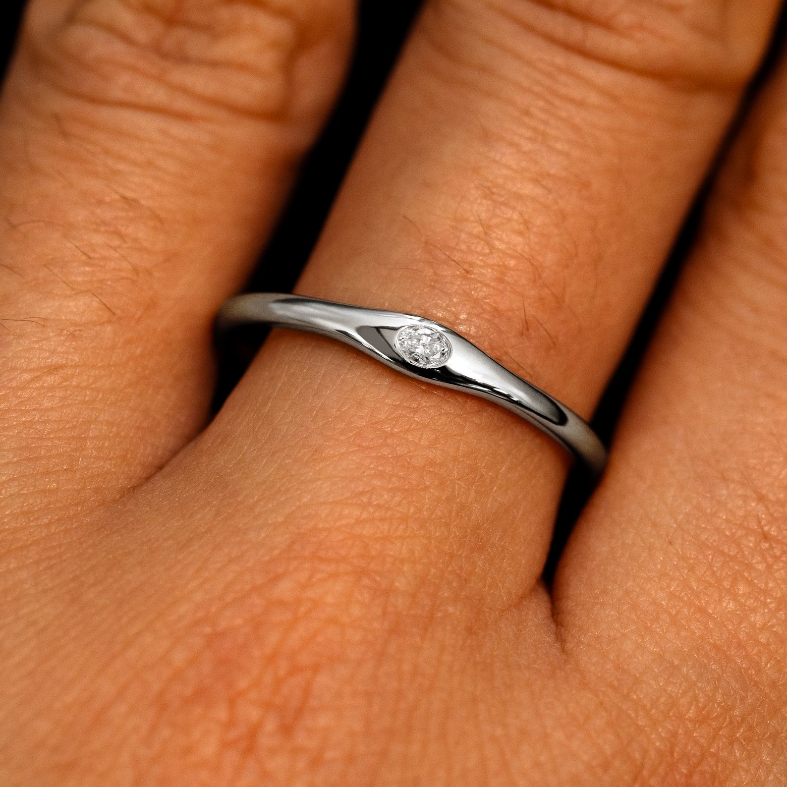 A 950 platinum Flush Set Oval Diamond Ring on a model's finger