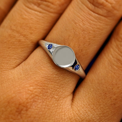 Close up view of a model's fingers wearing a 950 platinum Gemstone Signet Ring in sapphire