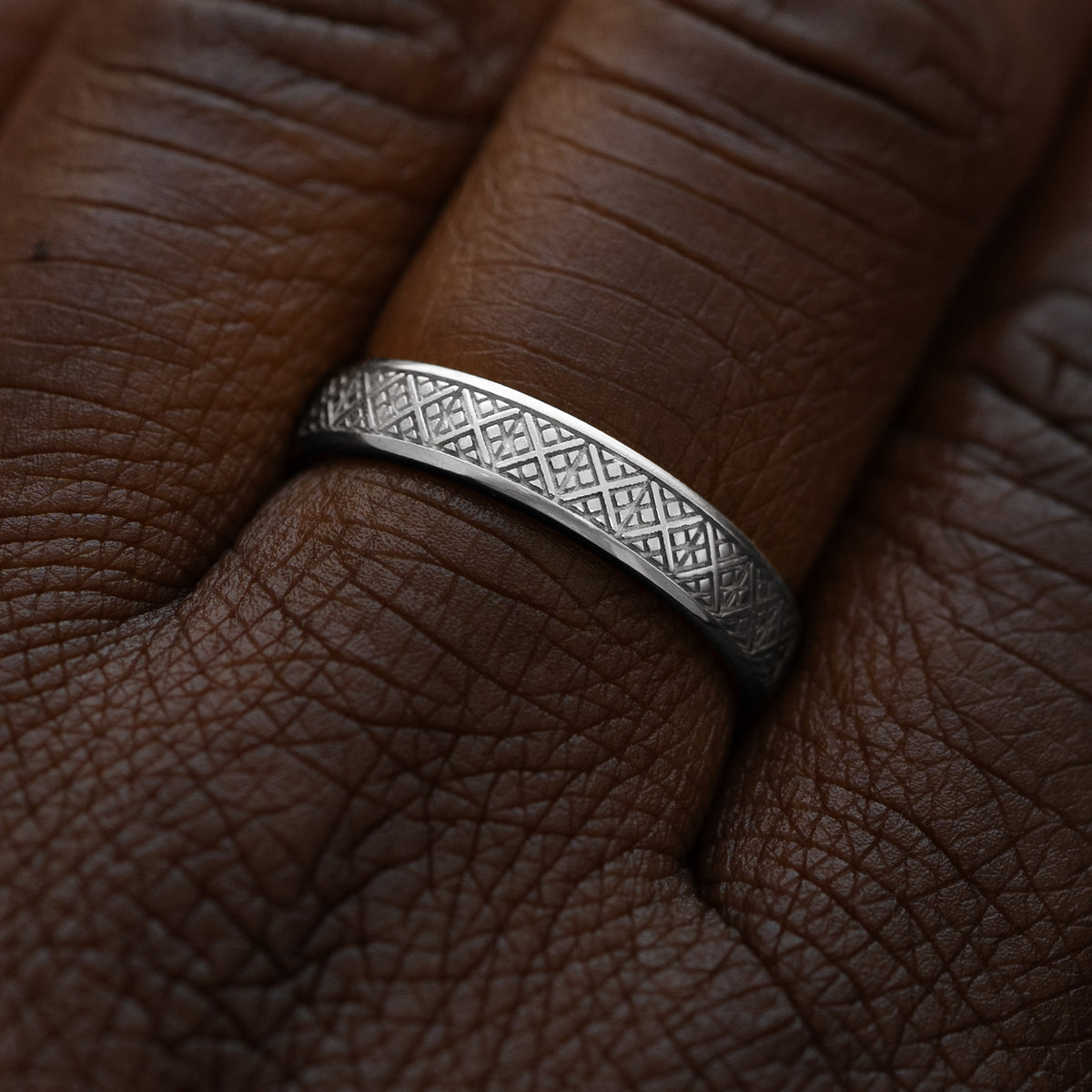 Close up view of a model wearing a solid 950 platinum diamond patterned band