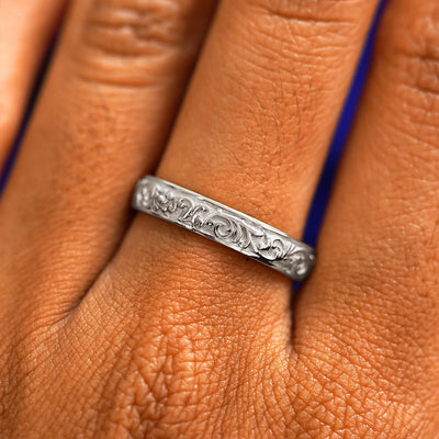 Close up view of a model's hand wearing a platinum Filigree band