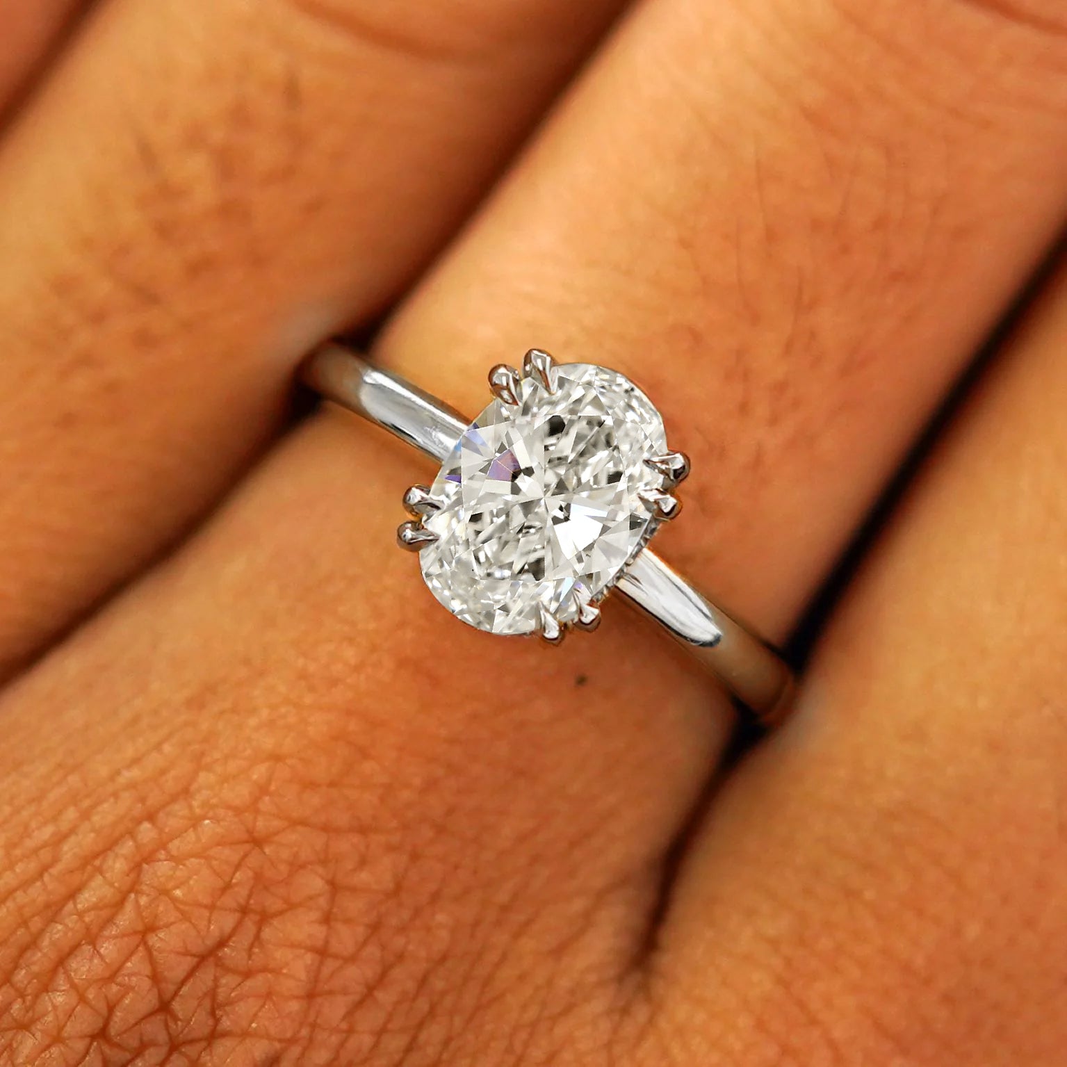 Close up view of a model's fingers wearing a 950 platinum Oval Moissanite Halo Ring