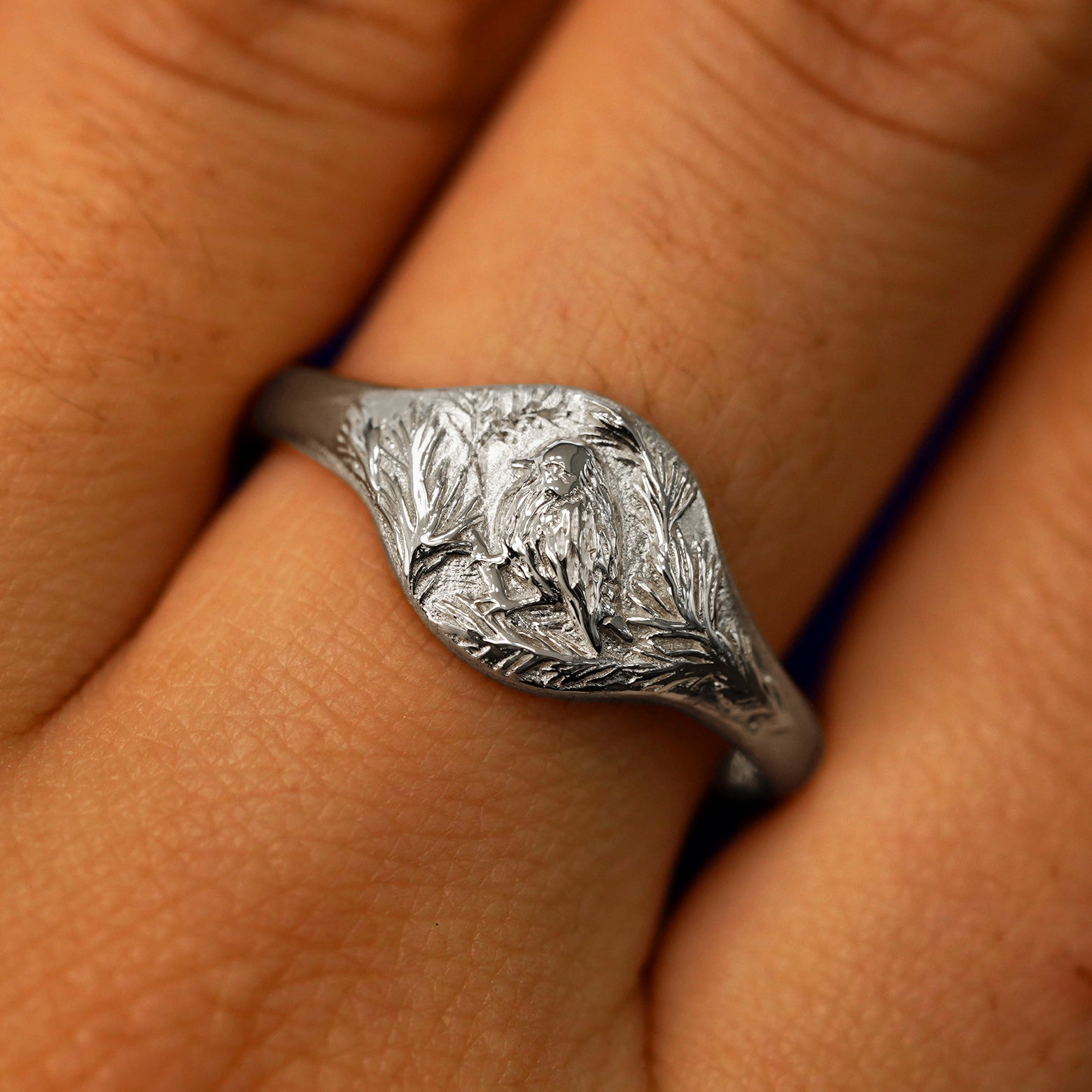 Close up view of a model's fingers wearing a 950 platinum Pine and Bird Signet Ring