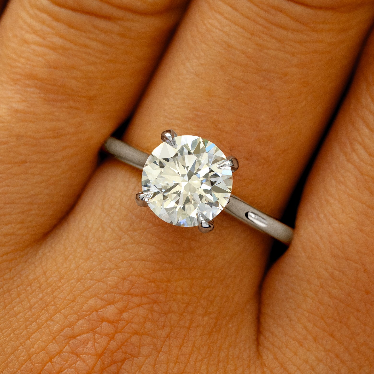 A solid 950 platinum Round Lab Diamond Cathedral Set Ring on a model's finger